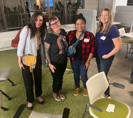 Four women of the User Experience Professionals Association of Minnesota posing and smiling post meeting.